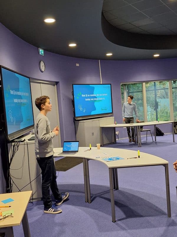 Een leerling presenteert bij twee schermen met de vraag over een kortere lesdag
